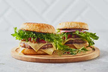 Two burgers with veal cutlet and herbs on wooden cutting board