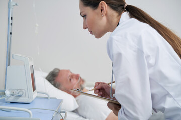 Concentrated female physician checking male vital signs