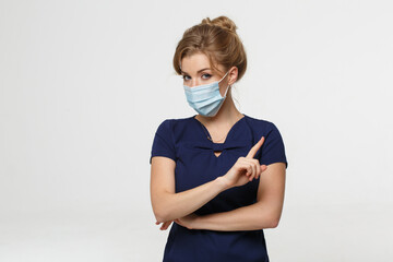 Female medic in a disposable medical mask isolated on a light background.