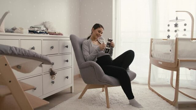 Wide shot video of caucasian woman in advanced pregnancy browsing ultrasound scan in baby's room. Shot with RED helium camera in 8K.