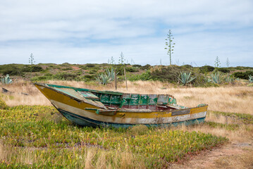 weathered old fishing boat in dune landscape, algarve coast