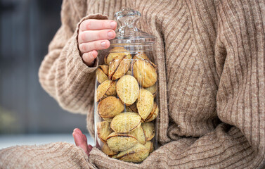 Glass jar with cookies nuts with condensed milk in female hands.