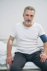 Sick man getting supplemental oxygen through nose tubes