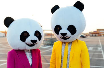 Storytelling image of a couple wearing giant panda head. Man and woman celebrating outdoor and...