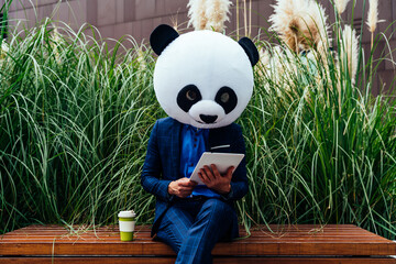 Storytelling image of a business man wearing a giant panda head. Funny cinematic concept about a...