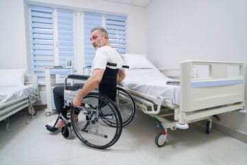 Disabled man seated in wheeled chair in hospital ward