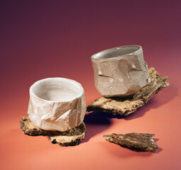 Two ceramic bowls, handmade in Japanese style, stand on a wooden bark. Wabi sabi style.