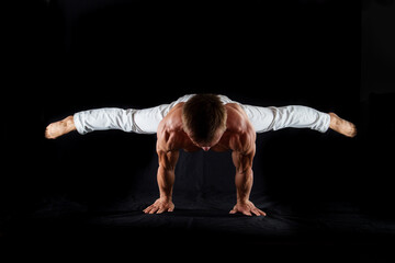 circus artist keeps balance on one hand isolated on a black background. Concept of willpower, motivation and healthy lifestyle