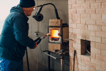 Blacksmith forge oven with hot flame. Smith put in and heating iron piece of steel in fire of red hot forge oven