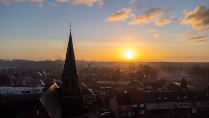 Fototapeta premium Cityscape silhouette of catholic church tower in Sint Jozef, Rijkevorsel, Belgium on a wonderful orange blue evening sky background. Cityscapes and religion concepts. High quality photo