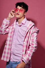 portrait of a young man in pink glasses pink blazer posing studio isolated background unaltered