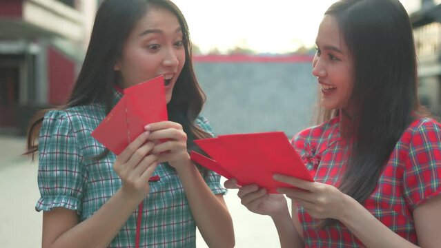 Beautiful Asian woman wearing a traditional red cheongsam on Chinese New Year.Hand holding red envelope or Ang pao with Chinese character means happiness or good fortune.