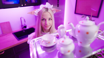 Blonde pink retro maid with pointy ears at home offer tray with tea cups