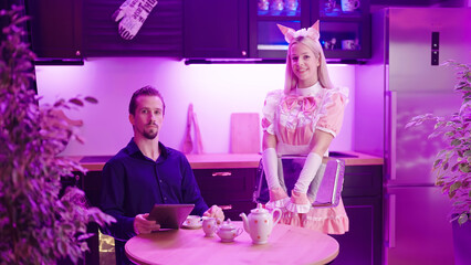 Retro maid in pink uniform serving tea to male master reading tablet news - obrazy, fototapety, plakaty