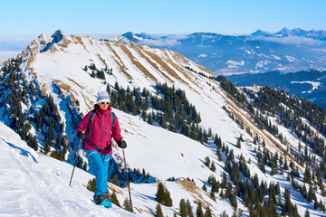 nice senior woman snowshoeing on the Nagelfluh mountain chain above a sea of fog over Bregenz Wald mountains, Hochgrat, Steibis,Bavarian alps, Germany 