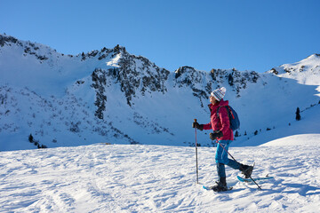 Fototapeta na wymiar nice senior woman snowshoeing in the snowy landscape of Kleinwalsertal in Vorarlberg, Austria