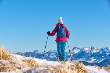  nice senior woman snowshoeing on the Nagelfluh chain above a sea of fog over Bregenz Wald...