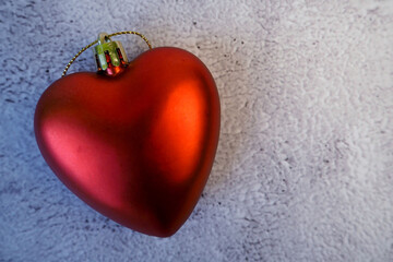 a Christmas toy in the form of a red heart lies on a gray background. top view. decoration 