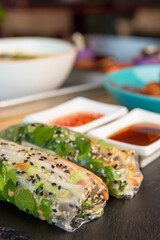 Fresh assorted Asian spring rolls with shrimps, vegetables, fruit over rustic concrete background.