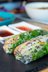 Fresh assorted Asian spring rolls with shrimps, vegetables, fruit over rustic concrete background.