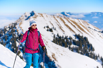 nice senior woman snowshoeing on the Nagelfluh mountain chain above a sea of fog over Bregenz Wald...