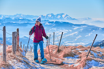  nice senior woman snowshoeing on the Nagelfluh chain above a sea of fog over Bregenz Wald...