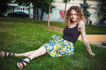 Curly-haired woman sitting on the grass