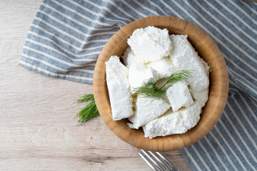 Traditional homemade salted cottage cheese cheese in a wooden bowl