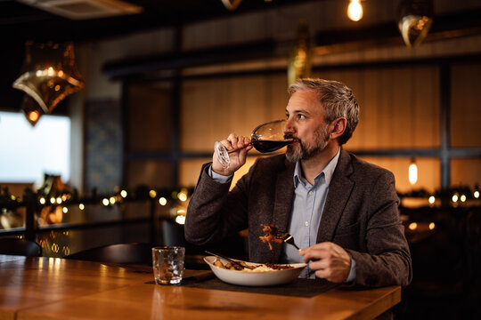 Serious caucasian food critic, enjoying the quality food in a restaurant.