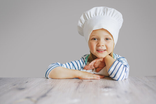 happy cute little kid girl wear chef uniform and cooking a birthday cake