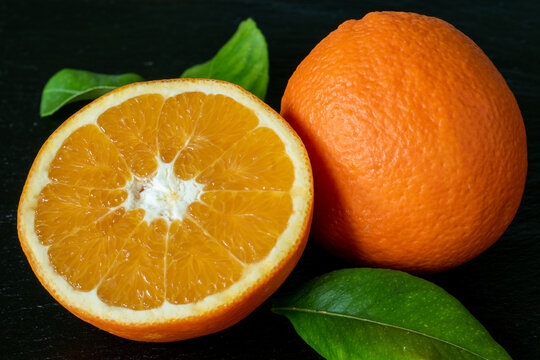 Naranjas org&aacute;nicas veganas, naturales, reci&eacute;n cogidas del &aacute;lbol. Hojas verdes, fondo negro.
