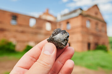 Smoke whirling around small meteorite stone in hands close-up.