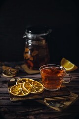 Healthy food concept, hot citrus tea in transparent cup and circles of orange, low key photo, vertical