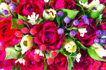 A beautiful bouquet of flowers made of red and yellow roses, green leaves and red and purple berries. Top view. Close-up.
