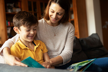 Fototapeta premium Mother and son reading a book. Little boy enjoy with mom reading a book..