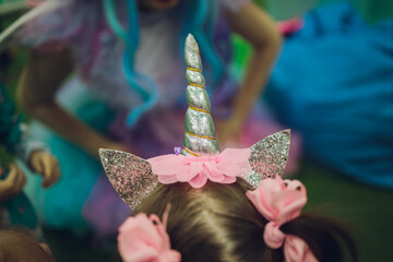 little girl wearing unicorn headband with pink background. Portrait of cute smiling child with...