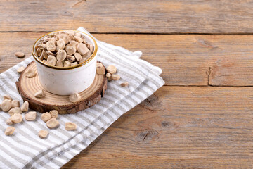 Cicerchia or indian pea on a ceramic bowl with napkin on natural wooden background, close up. Legumes known as Lathyrus Sativus, Chickling Vetch, Blue Sweet Pea made in Puglia, copy space