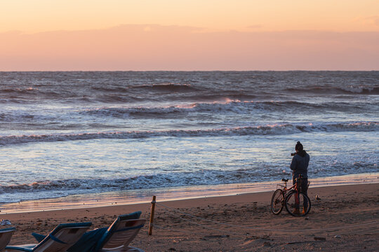cyclist takes pictures and enjoy the sunset over the sea with a beautiful horizon. Wonders of nature. Beautiful landscape of the winter sea.