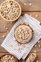 Fototapeta premium Cicerchia or indian pea on a bowls with napkin on natural wooden background, gluten free food. Legumes known as Lathyrus Sativus, Chickling Vetch, Blue Sweet Pea made in Puglia, top view, flat lay