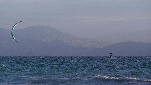 Kiteboarding. Kite surfer rides the waves, Tarifa Spain. Sports activity. Kitesurfing action. Slow motion.
