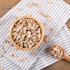 Cicerchia or indian pea on a wooden bowl with napkin on natural wooden background, gluten free food. Legumes known as Lathyrus Sativus, Chickling Vetch, Blue Sweet Pea made in Puglia, top view