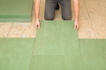 Man hands laying green natural wood fiber insulation board. Preparing surface from fibreboard...