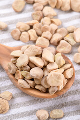 Dry Cicerchia or indian pea on a wooden spoon on a cotton napkin, close up, food gluten free. Legumes known as Lathyrus Sativus, Chickling Vetch, Blue Sweet Pea made in Puglia, top view