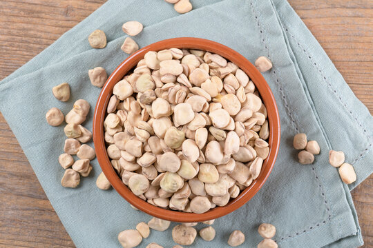 Cicerchia or indian pea on a clay bowl with napkin on natural wooden background, food gluten free. Legumes known as Lathyrus Sativus, Chickling Vetch, Blue Sweet Pea made in Puglia, top view, flat lay