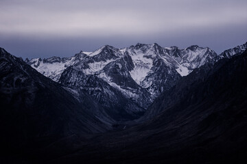 A beautiful view of rocky mountains covered with snow at dusk in the winter