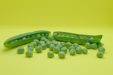 Organic green peas, freshly picked and peeled from the pod, on the yellow background. Concept of...