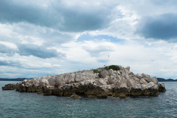 Small isolated rocky islet with seagulls in Adriatic sea, Croatia, Zadar region