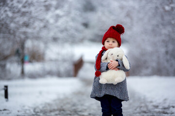 Beautiful toddler child, cute boy, playing in snowy park winter time