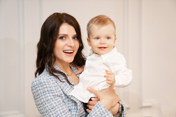 a beautiful dark-haired woman holds a one-year-old boy in her arms. 