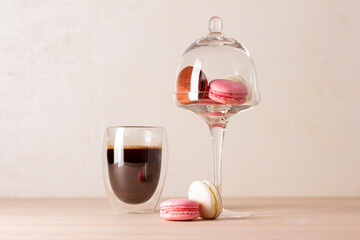 Tasty macaroons on cake stand with dome